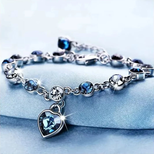 Pulseira feminina prateada da sorte com pingente de coração de cristal azul.